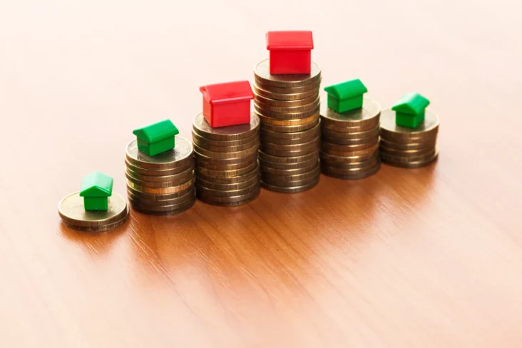 Imagem com casinhas de brincar em cima de colunas feitas de moedas