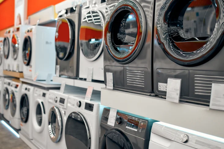 Várias máquinas de lavar roupa, novas, numa loja de eletrodomésticos