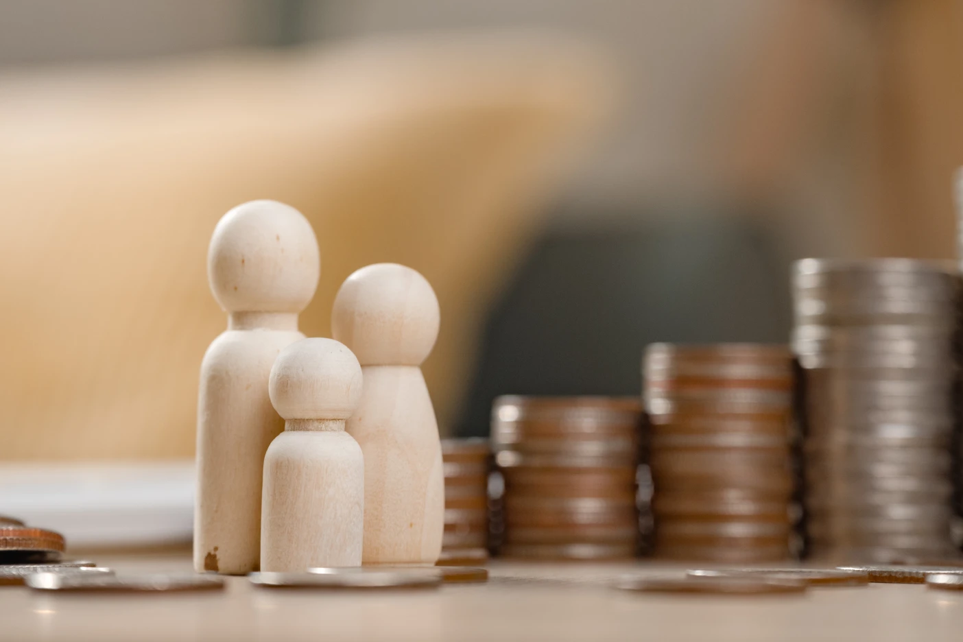 Imagem de uma família de bonecos de madeira em frente a uma pilha de moedas