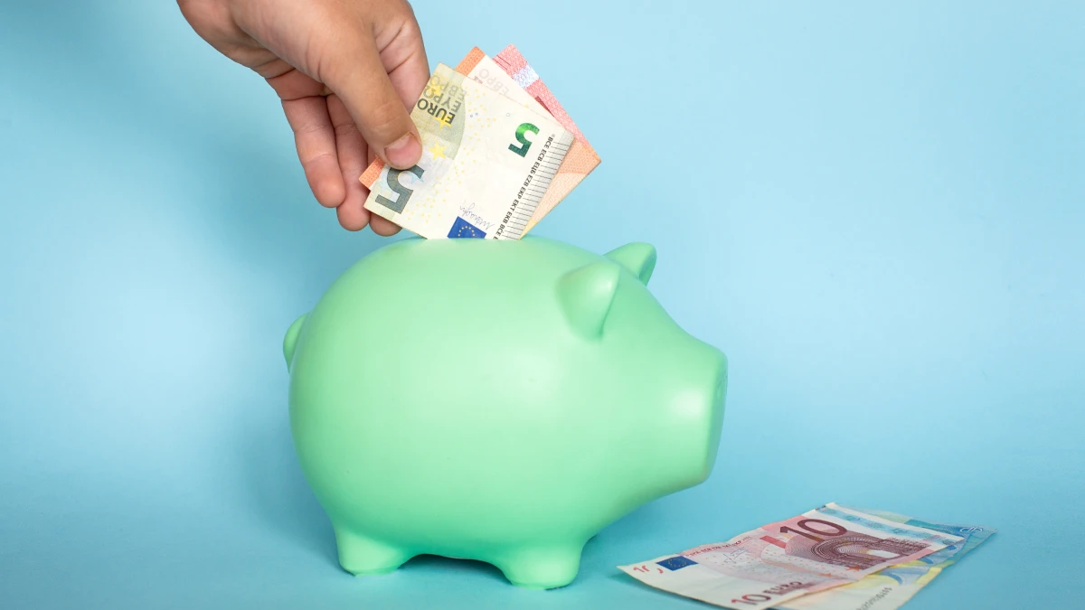 Poupança automática: Configure de forma prática e segura Imagem de notas a serem guardadas num porquinho mealheiro