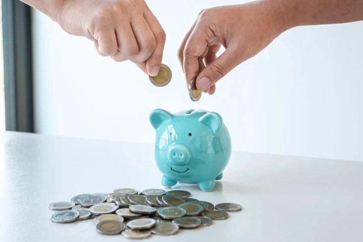 Casal guarda moedas num mealheiro