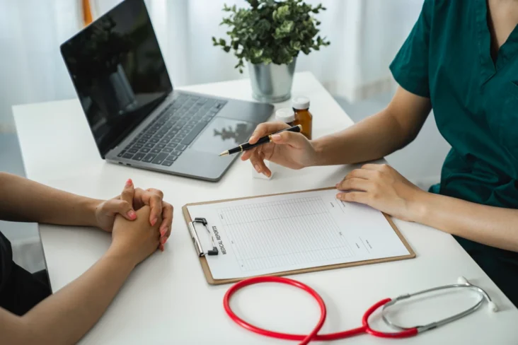 Imagem onde uma médica fala e aponta registos do paciente