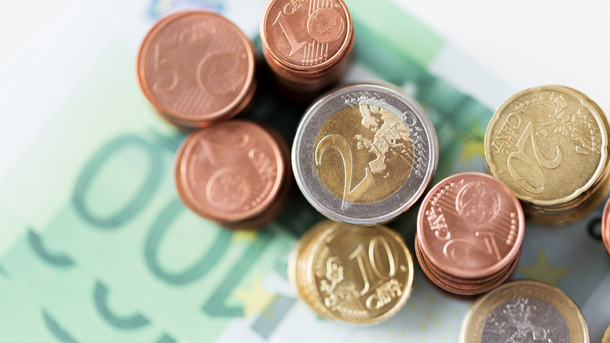 Várias moedas de euro sobre notas de 100 euros