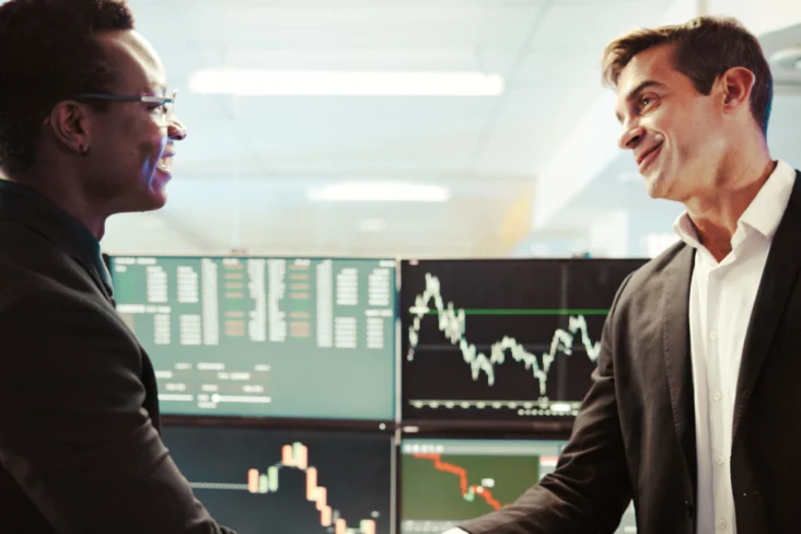 Mulher e homem apertam as mãos após um negócio de venda de ações