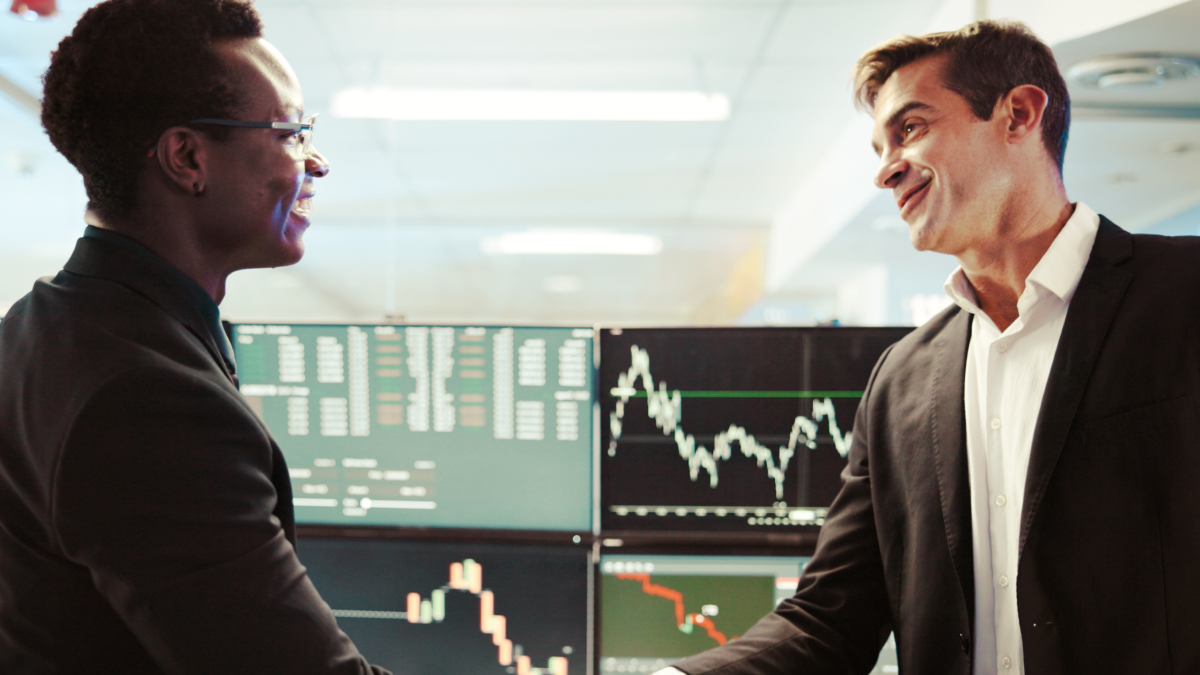 Mulher e homem apertam as mãos após um negócio de venda de ações