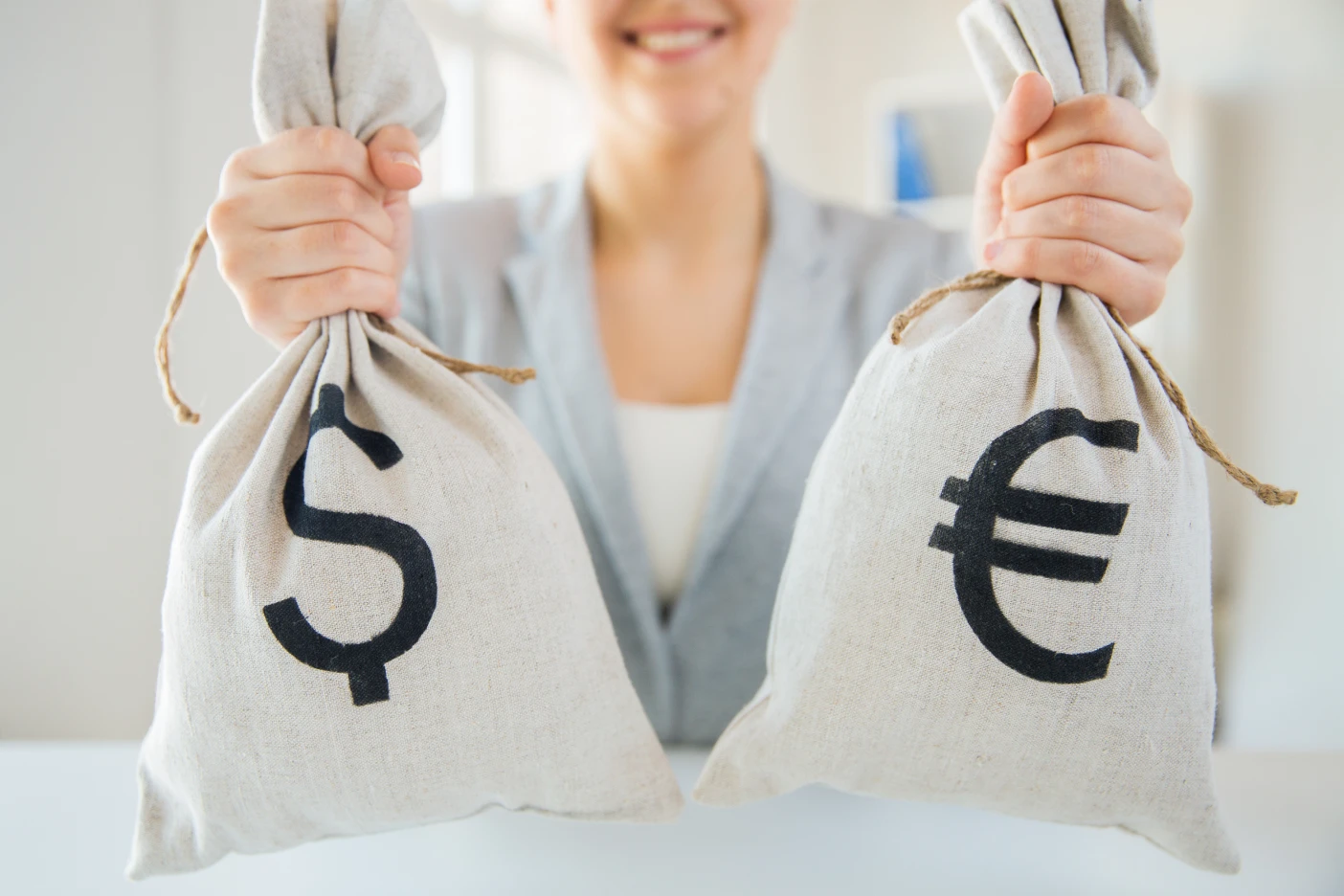 Imagem onde uma mulher agarra em dois sacos de dineiro, um com o símbolo de Euro e outro com símbolo de Dólar