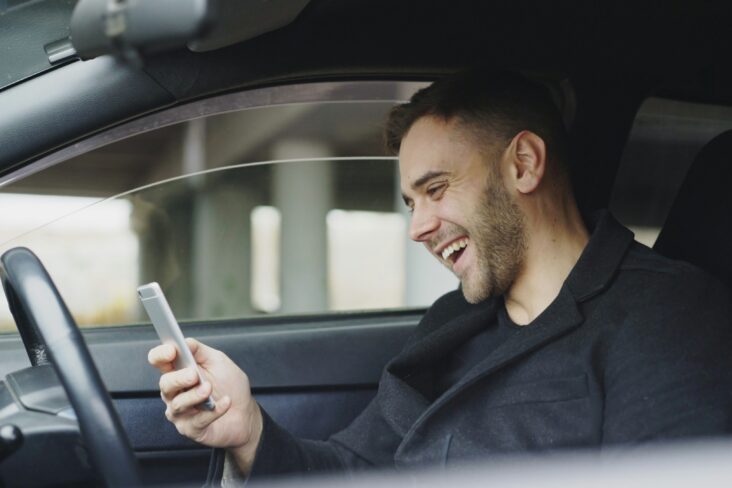 Homem dentro de um carro feliz por ter poupado com a transferência do seu crédito automóvel com a ajuda do Doutor Finanças