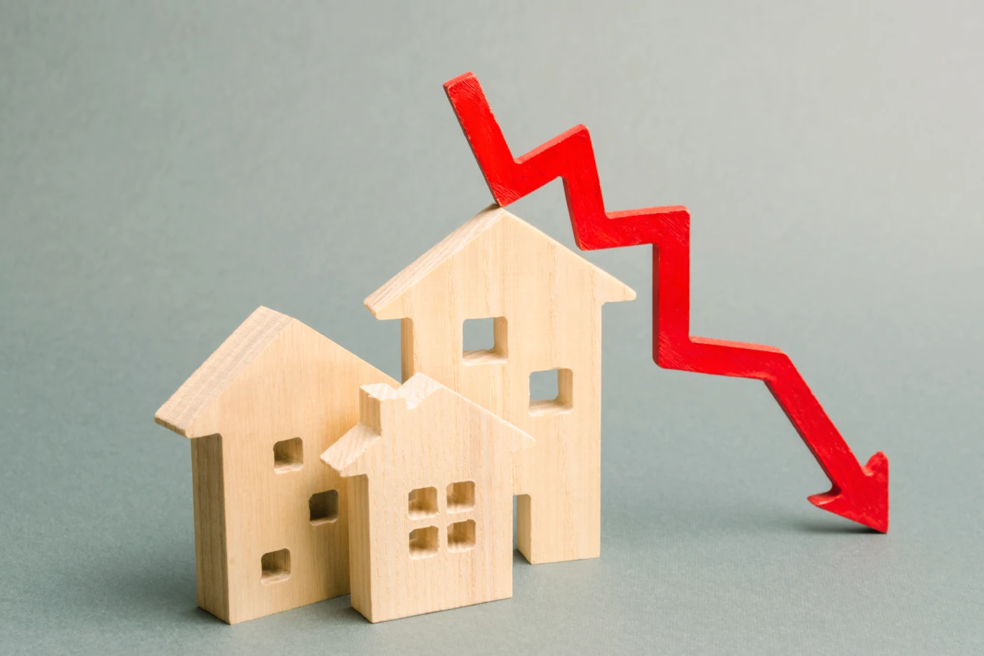 Imagem de casinhas de madeira com uma seta vermelha em queda