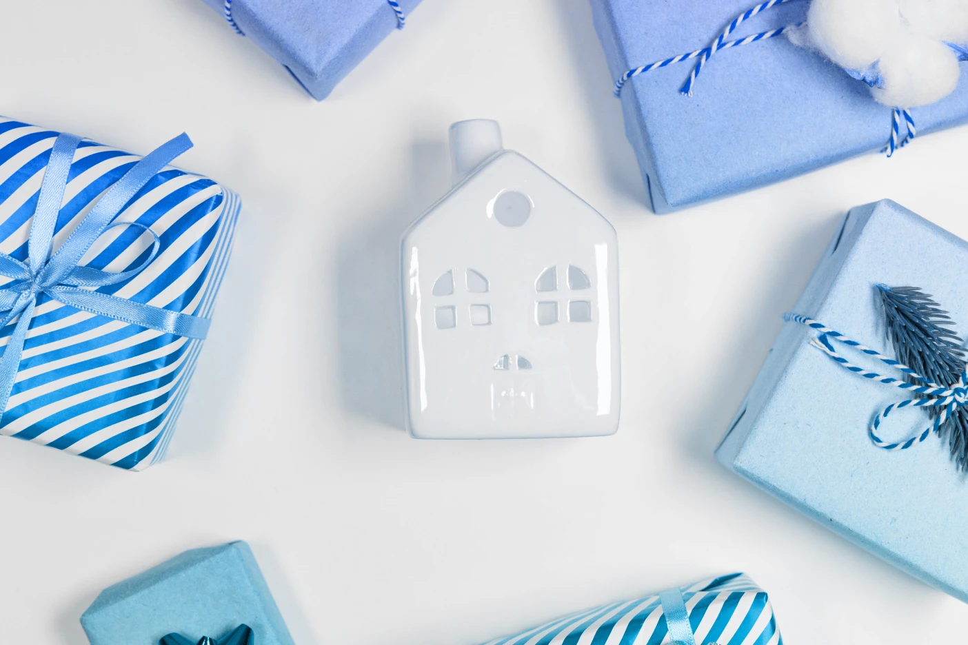 E se usar o subsídio de Natal para amortizar o crédito habitação? Imagem de uma casa de cerâmica rodeada de presentes de Natal