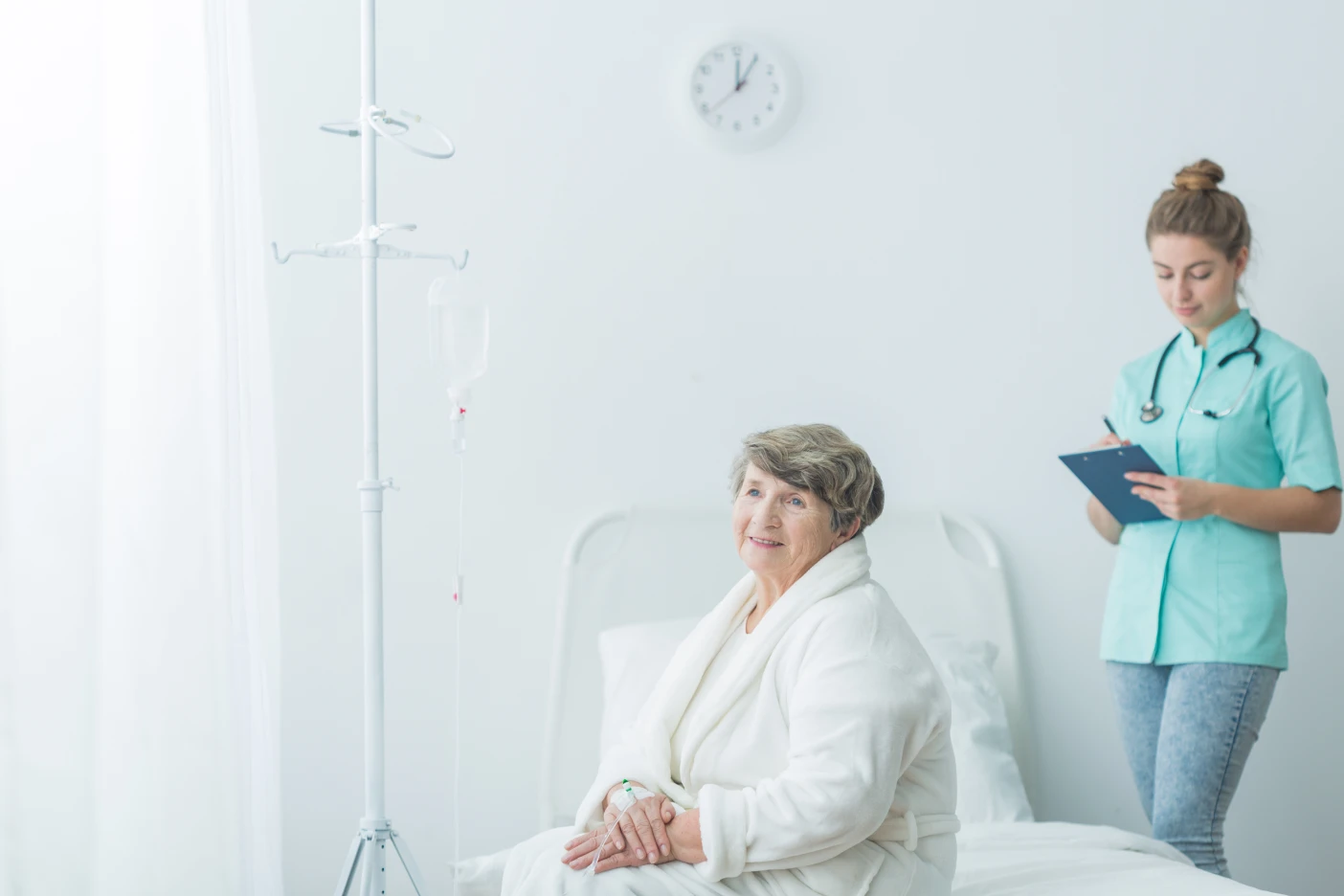 Imagem de uma idosa sentada numa cama de hospital, após uma operação bem sucedida