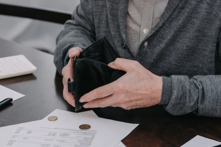 Imagem de um idoso a contar dinheiro na carteira para pagar as contas