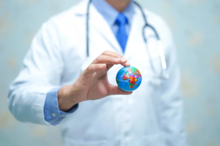 Imagem onde um médico segura um globo terrestre