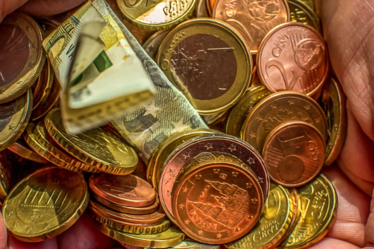 Imagem de uma mão a segurar em moedas e notas amarrotadas