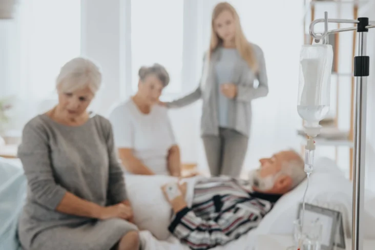 Imagem que representa a morte de um homem idoso num hospital, rodeado pela sua família