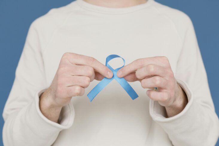 Novembro azul. Homem a segurar um laço azul para consciencializar para o cancro da próstata