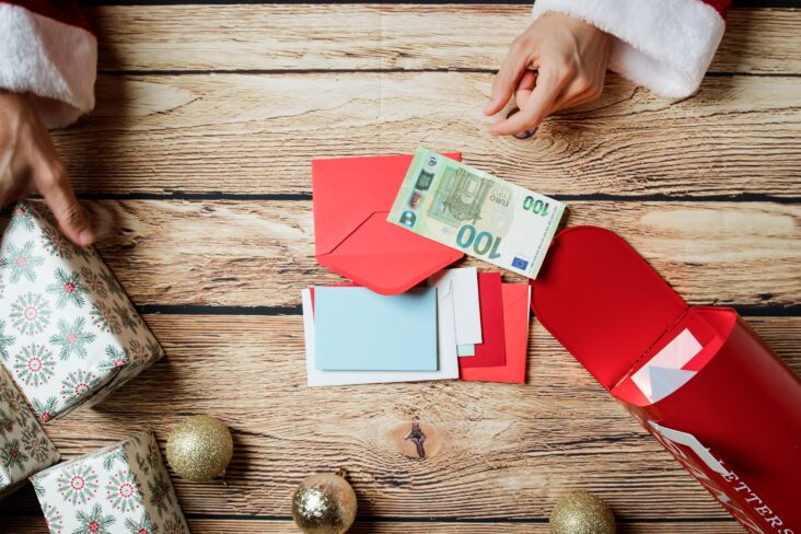 imagem de umas mãos do pai natal a mexer em embrulhos e envelopes com dinheiro - para ilustrar artigo sobre Subsídio de Natal: 5 erros que podem custar caro