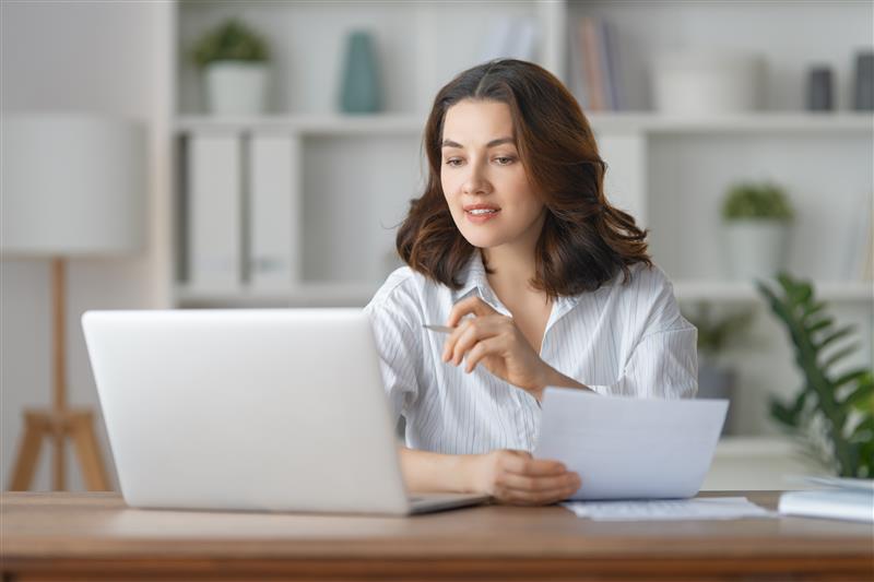 Mulher com documentos a usar computador