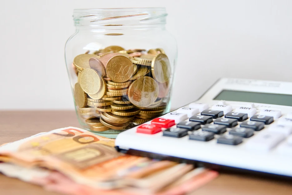 Resoluções financeiras de 2026: Como transformar objetivos em metas reais Imagem de notas e moedas com uma calculadora