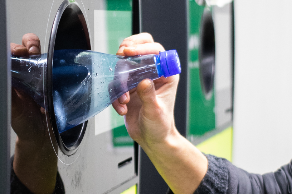 Garrafas e latas pagam depósito reembolsável a partir de abril. Como vai funcionar? Imagem onde um homem devolve uma garrafa de plástico num centro de recolha para receber o reembolso