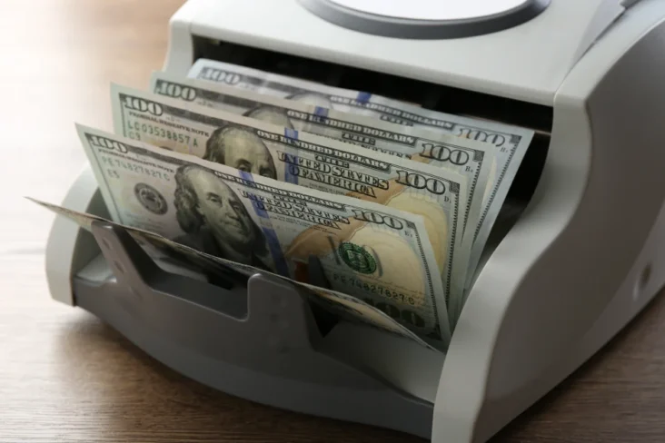 Imagem de uma máquina de contar dinheiro a somar notas de dólar