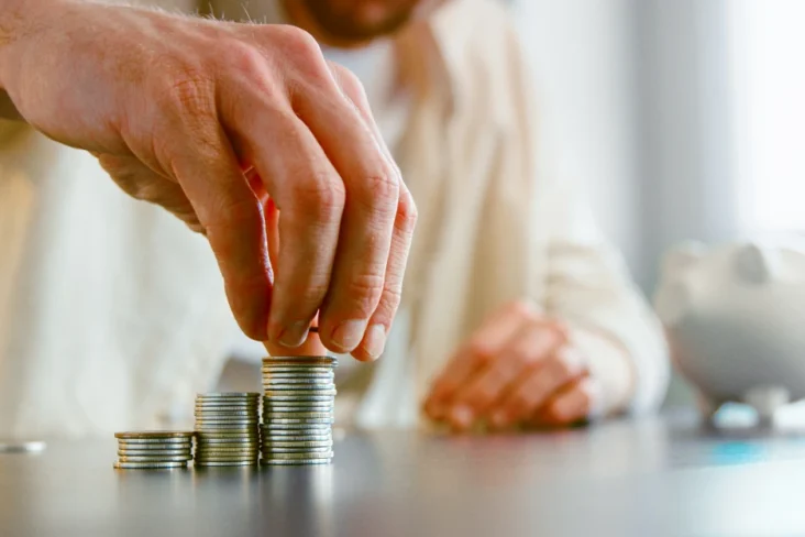 Imagem de um homem a montar torres com moedas