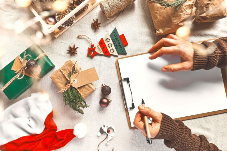 As mãos da mulher escrevem a lista de desejos de Natal ou lista de tarefas - para ilustrar artigo sobre orçamento de natal