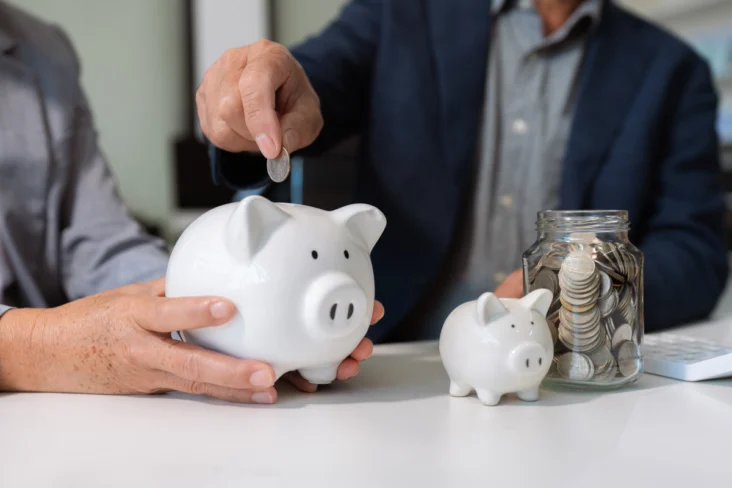 Duas pessoas com porquinhos mealheiros a ilustrar o investimento num ppr com capital garantido e num PPR em fundos