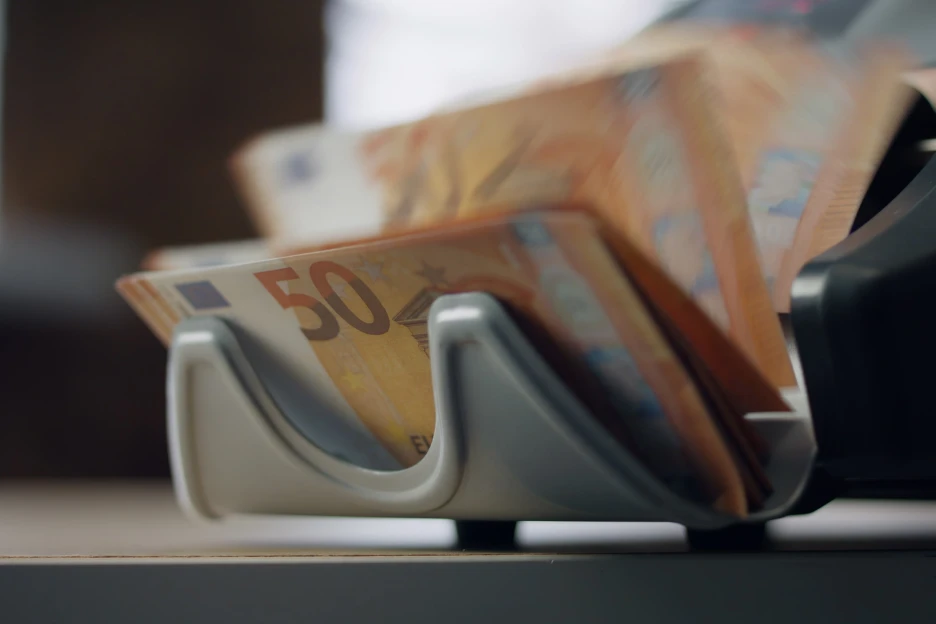 Imagem de notas de cinquenta euros numa máquina de contar