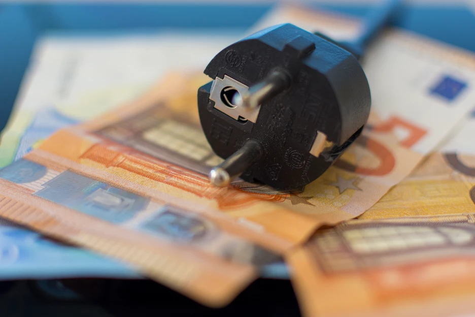 Imagem de uma ficha elétrica sobre várias notas de euros