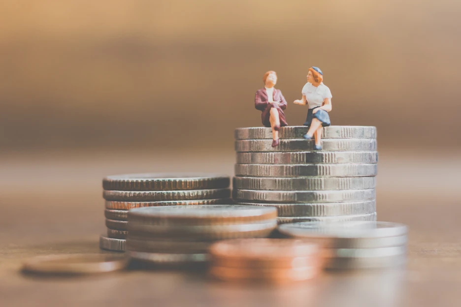 Imagem de um casal de bonecos sentados em moedas