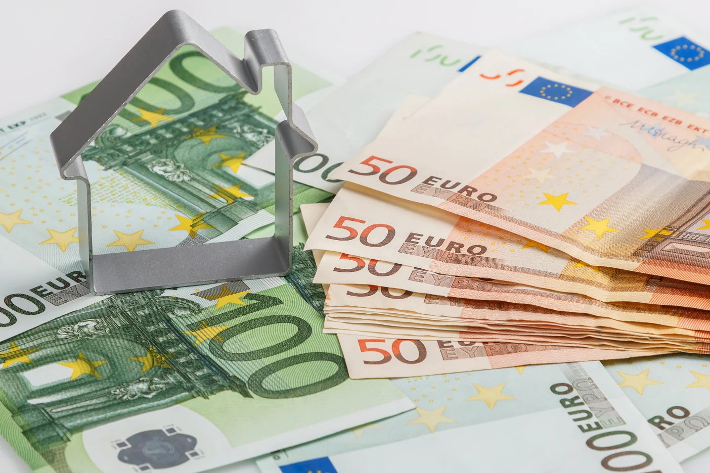 Como escolher entre taxa fixa e taxa variável no crédito habitação? Imagem de notas de euro com uma casa de metal