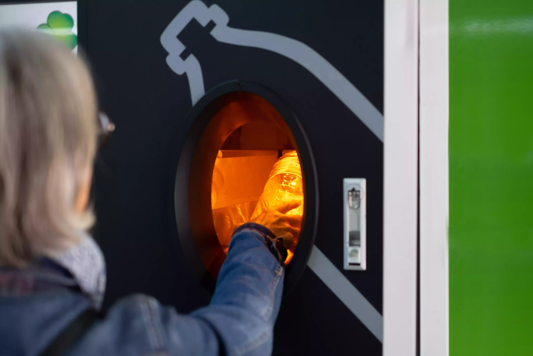 Mulher a colocar garrafa de plástico em máquina de recolha automática