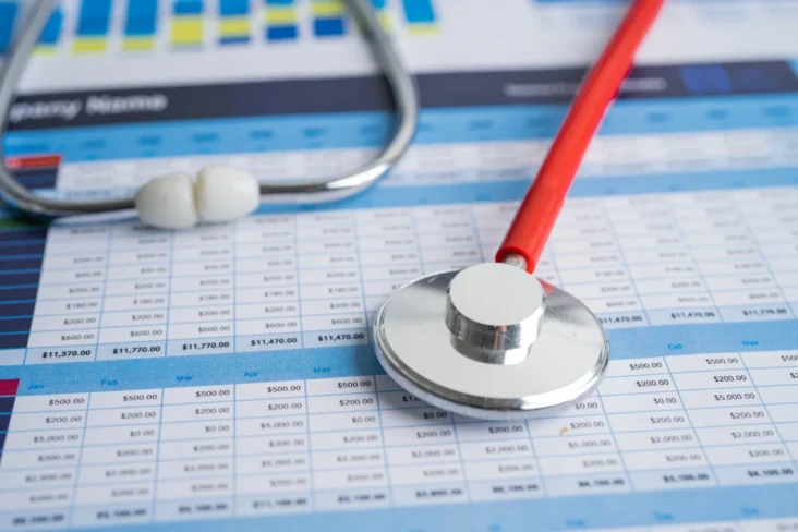 Imagem de um estetoscópio sobre tabela de preços de seguros de saúde