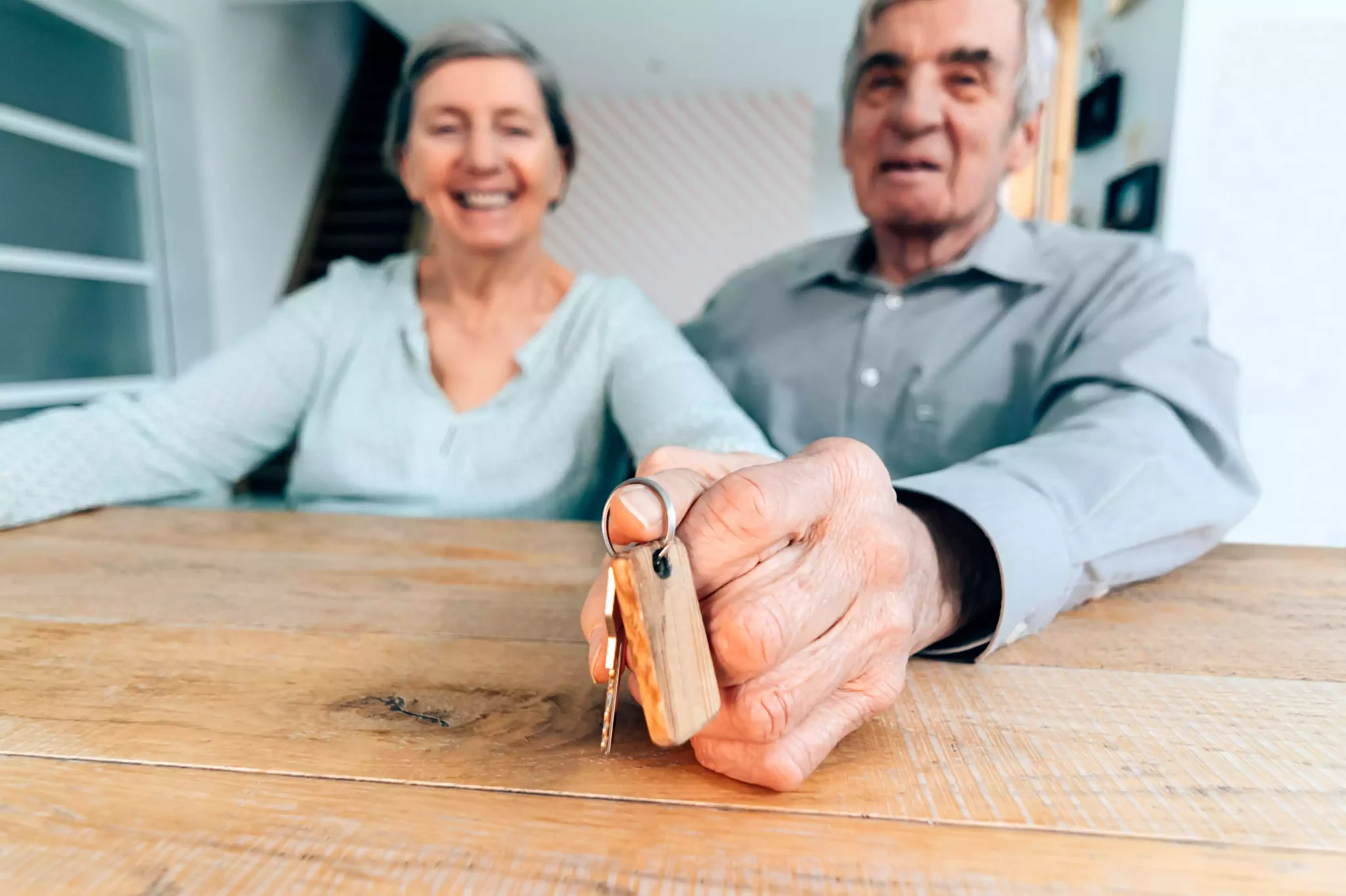 Vai vender a sua casa depois dos 65 anos? Saiba como ficar isento de mais-valias Casal de idosos a entregar chave de casa