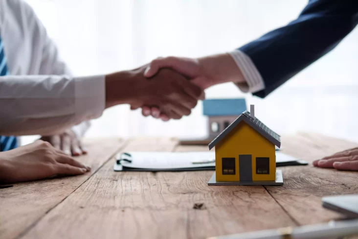 Pessoas a dar aperto de mão ao é de miniatura de casa