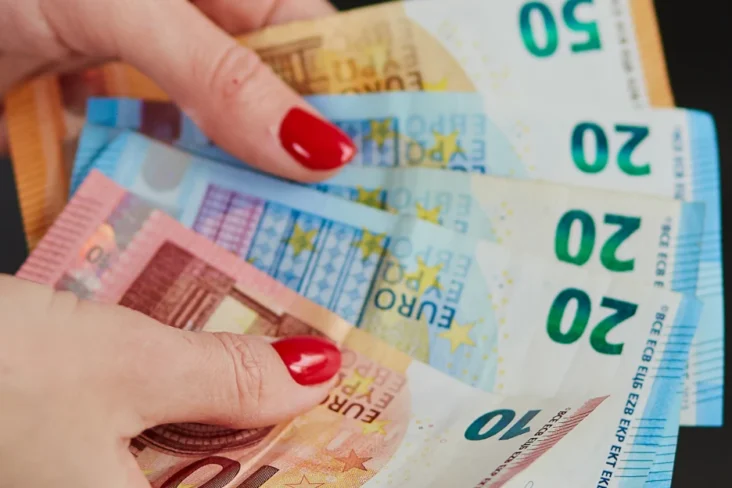 Imagem onde uma mulher segura em várias notas de euro