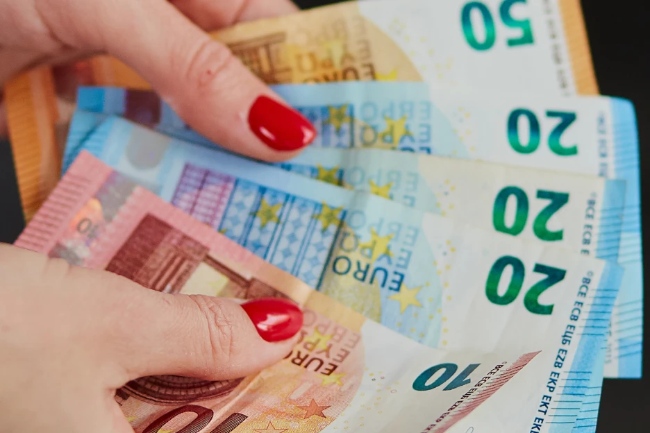 Como usar o reembolso do IRS para criar um fundo de emergência Imagem onde uma mulher segura em várias notas de euro