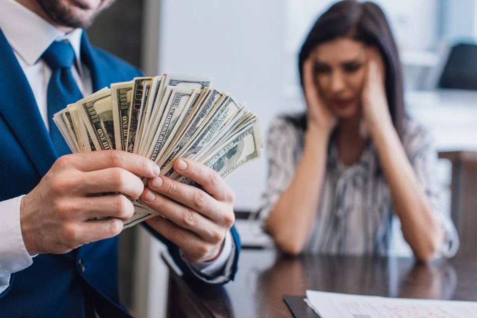 Imagem de um homem com imensas notas nas mãos, no fundo vê-se uma mulher claramente desesperada com a sua relação