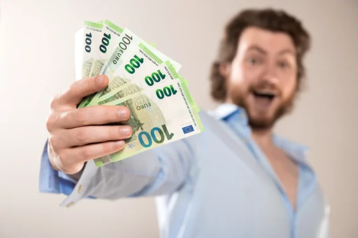 Imagem onde um homem feliz segura várias notas de euro