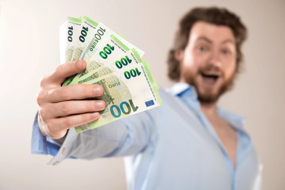 Liberdade financeira: Como começar? Imagem onde um homem feliz segura várias notas de euro