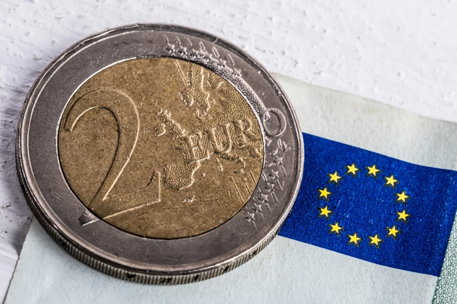 Imagem de uma moeda de euro sobre a bandeira da União Europeia