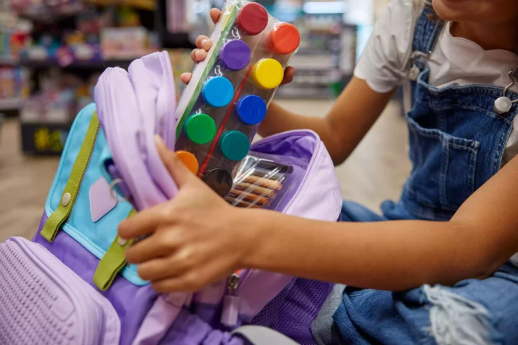 Criança a arrumar material escolar na mochila