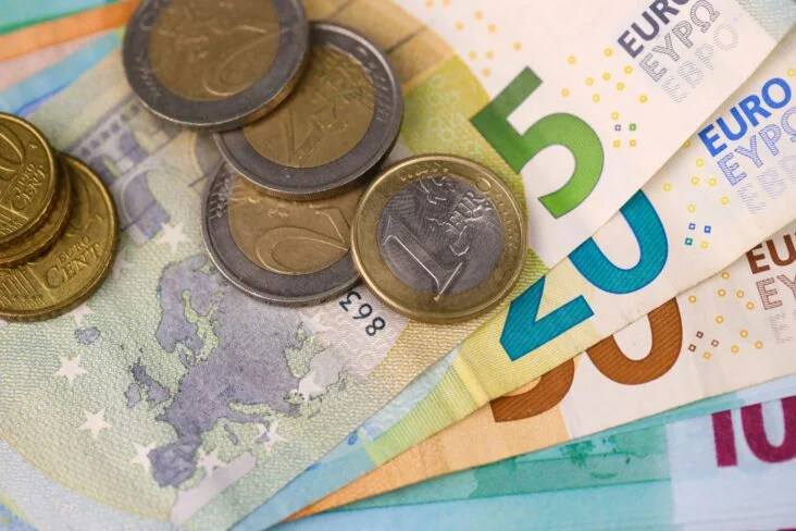Moedas de 1 e 2 euros e notas de 5, 20 e 50 euros, espalhadas em cima de uma mesa