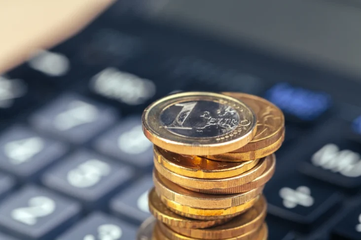 Imagem de moedas de euro e uma calculadora básica