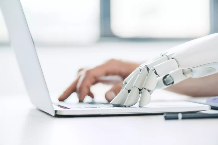 Mão humana e mão de robô no computador