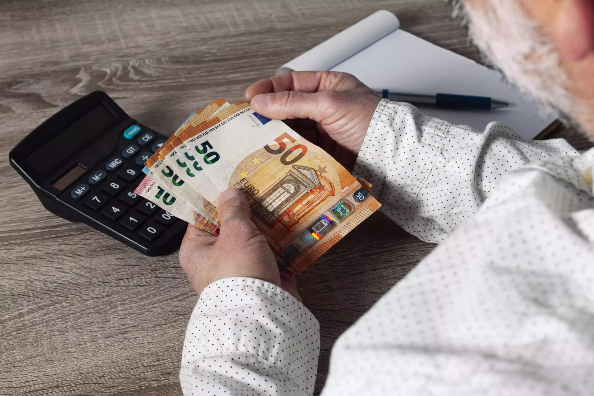 Retenção na fonte desce 50% em novembro. Saiba quanto vai receber Homem com notas de euros a usar calculadora